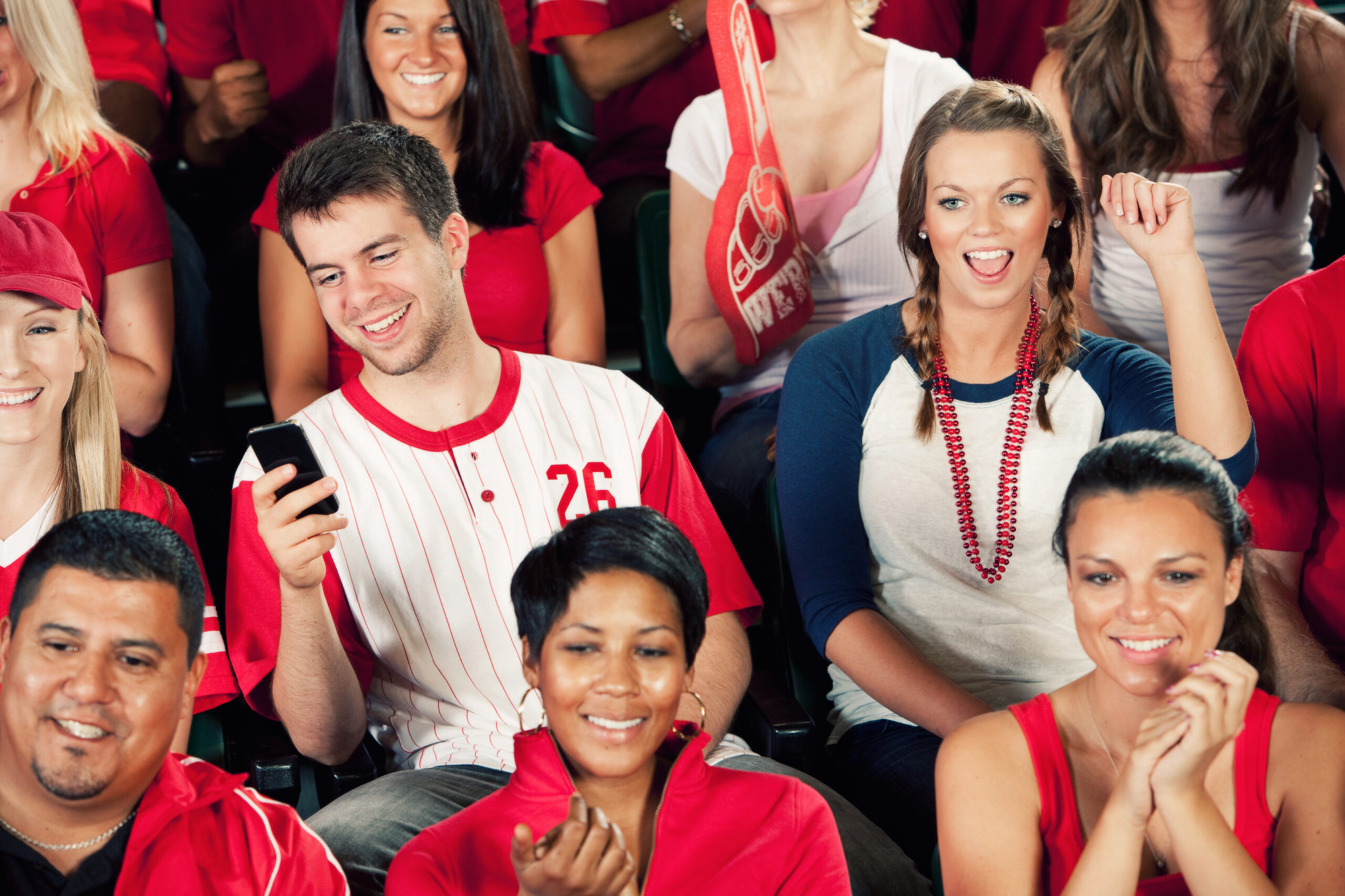 photo of man in a cap watching a game with smartphone and earpiece